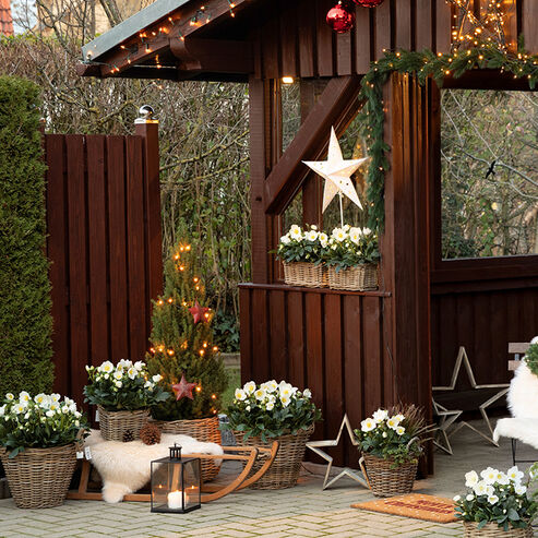 Decorated with fairy lights, fir greenery, candle arrangements and Christmas balls, the garden house is transformed into a Christmas market hut.