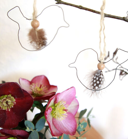 Wire birds as a spring decoration next to a bouquet of Snow Roses.